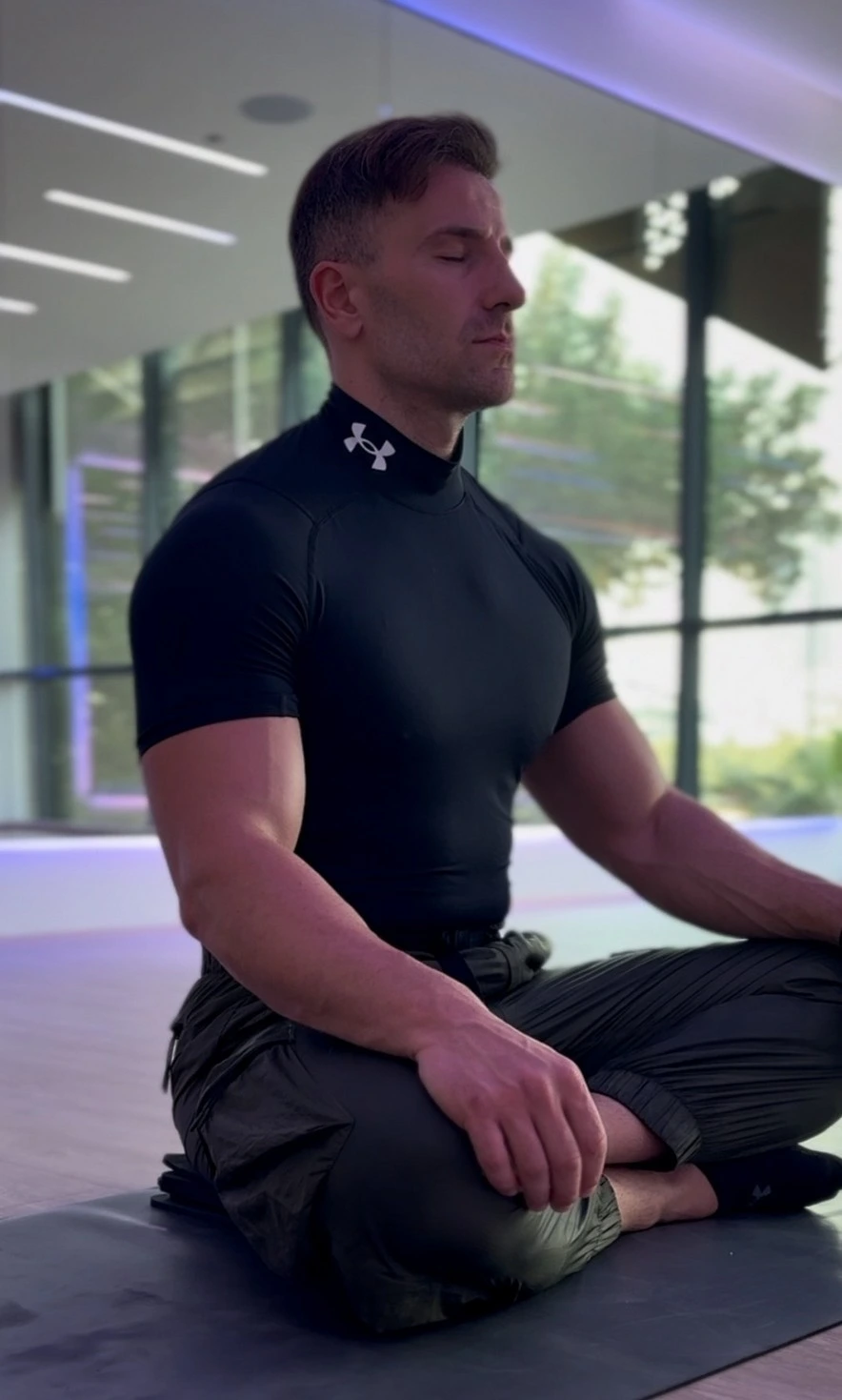 Driton sitzt bei der Meditation auf einer Matte